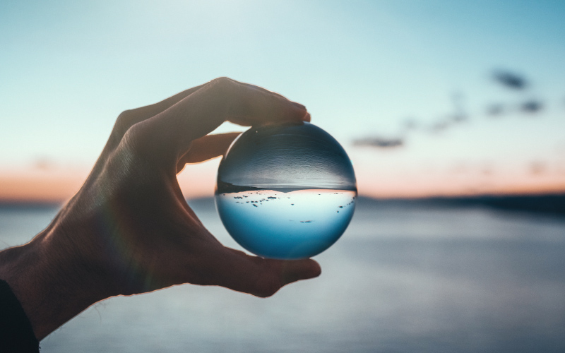 Hand holding a crystal ball that reverses the image of horizon
